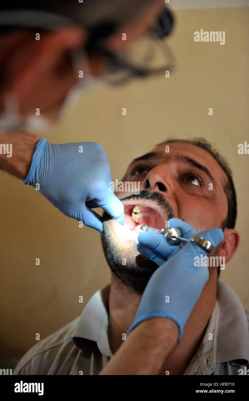 (100929-N-6027B) US Airforce Dental Tech zugewiesen, zivile Angelegenheiten-Task-Force Balad, untersucht und spritzt betäubende Wirkstoffe in einem irakischen Patienten Zahnfleischrand in Vorbereitung bei der Entfernung von einer Weisheitszahn auf die militärische zivilen medizinischen Operation(MCMO) in Bayji, Irak am 29. September 2010. Foto: U.S. Navy MC2 Devin Brown Dental Care 341126 Stockfoto
