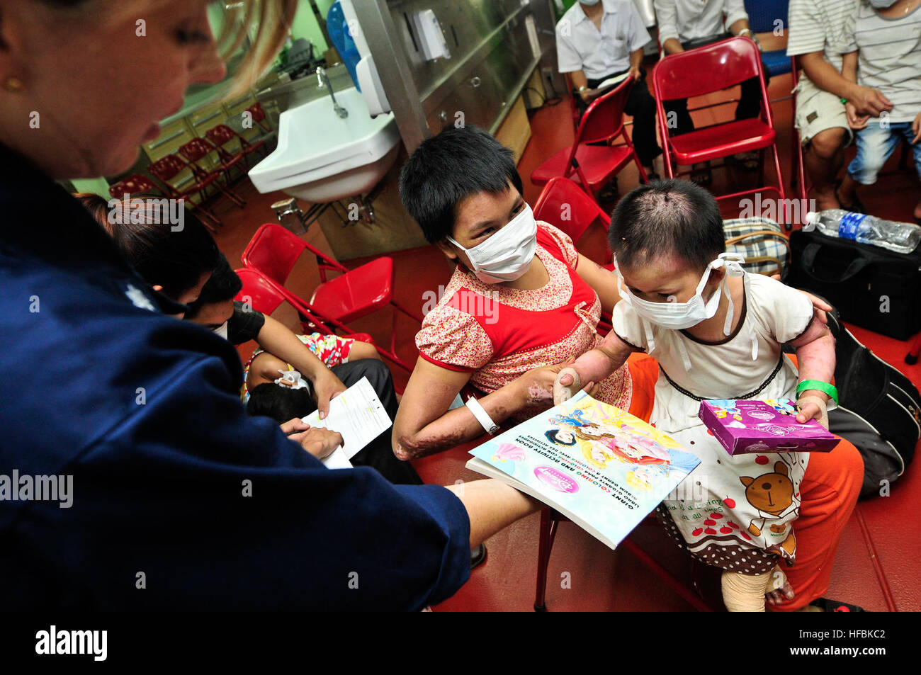 120711-O-ZZ999-009 VINH CITY, Vietnam (11. Juli 2012) CMdR Danielle Taysom Hände eine Malbuch, einem drei-Jahr-alten vietnamesischen Mädchen mit Verbrennungen dritten Grades, während ein Patient in-Flow an Bord der Military Sealift Command Lazarettschiff USNS Mercy (T-AH 19) als Teil des Pazifischen Partnerschaft 2012. Vietnam ist die dritte Station für Pacific Partnership 2012. Jetzt ist in seinem siebten Jahr pazifische Partnerschaft eine US-Pazifikflotte humanitäre und Bürgerbeteiligung Mission US-Militär, Host und Partnerstaaten, nicht-Regierungs-Organisationen und internationalen Organisationen entwickelt, um engere Beziehungen zu bauen Stockfoto