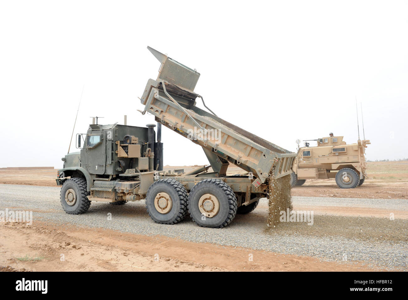 Der Provinz HELMAND, Afghanistan (19. April 2012) A Dump Truck betrieben durch eine Seabee zugewiesen Naval Mobile Bau Bataillon (NMCB) 11 Deponien Kies für ein Straßenbauprojekt in der südlichen Provinz Helmand, Afghanistan, da ein anderes Fahrzeug Sicherheit bietet. NMCB-11 ist in Gulfport, Mississippi, Gridley und ist im Einsatz in Afghanistan, General, Mobilität, Überlebensfähigkeit engineering Operationen, defensiven Operationen, Afghan National Army Partnerschaft und Ablösung der Einheiten in Afghanistan kombinierten und gemeinsame Operationen Bereich durchzuführen. (Foto: U.S. Navy Mass Communication Specialist 1. Klasse Jona Stockfoto