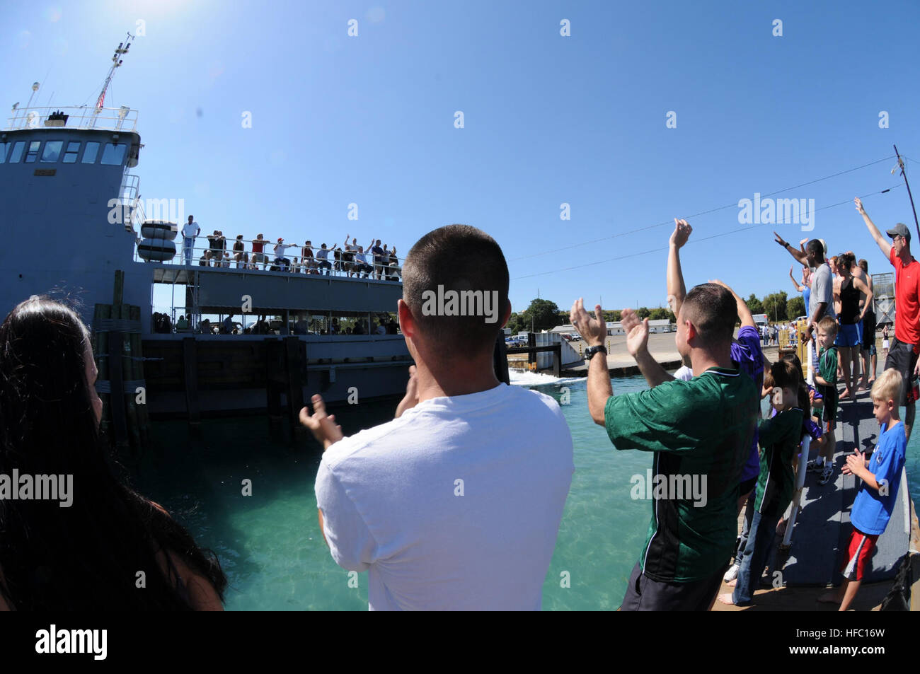 Mitglieder der Joint Task Force Guantanamo und Naval Station Gemeinschaft Welle Abschied an Kollegen, Freunde und Familienmitglieder, als sie das Boot zu verlassen, an der Basis Fähranleger, April 11 an Bord. Guantanamo-Bewohner üben eine lange Tradition der Sprung an der Pier ins Wasser manchmal in allen militärischen Uniform zu Ehren, die Freunde und Kollegen Service-Mitglieder, die ihre Touren auf der Karibikinsel abgeschlossen. JTF Guantanamo bietet sichere, humane, legale, transparente Pflege und Obhut der Gefangenen, einschließlich der Militärkommission und die verurteilten freigegeben von einem c bestellt Stockfoto