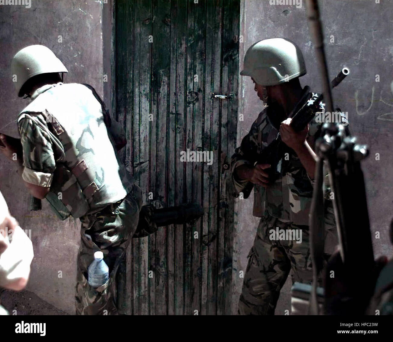 Zwei Mitglieder der Botswana Defense Force stehen in der Nähe einer Tür zu einem Gebäude.  Der Soldat auf der linken Seite beginnt an der Tür mit seinem rechten Bein.  Die Tür ist Teil eines Gebäudes auf dem Bakara-Markt in Mogadischu, Somalia.  Die Soldaten suchen nach Waffen bei einer Razzia auf dem Markt mit US-Marines (nicht dargestellt).  Diese Mission ist zur direkten Unterstützung der Operation Restore Hope. 2 BDF Soldaten auf Raid in Bakara-Markt 1993-01-30 Stockfoto