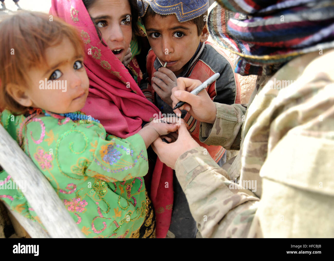 Ein Mitglied einer Koalition Special Operations Forces kulturellen Support Team markiert die Hand eines jungen Kindes um anzugeben, dass sie während einer medizinischen Klinik in Faiz Abad Horn, behandelt worden ist, Nawa District, Provinz Ghazni, Afghanistan Dez. 16.  Die Klinik war offen für Frauen und Kinder aus den Dörfern in die Faiz Abad Horn. MEDCAP 111216-N-MY805-024 Stockfoto