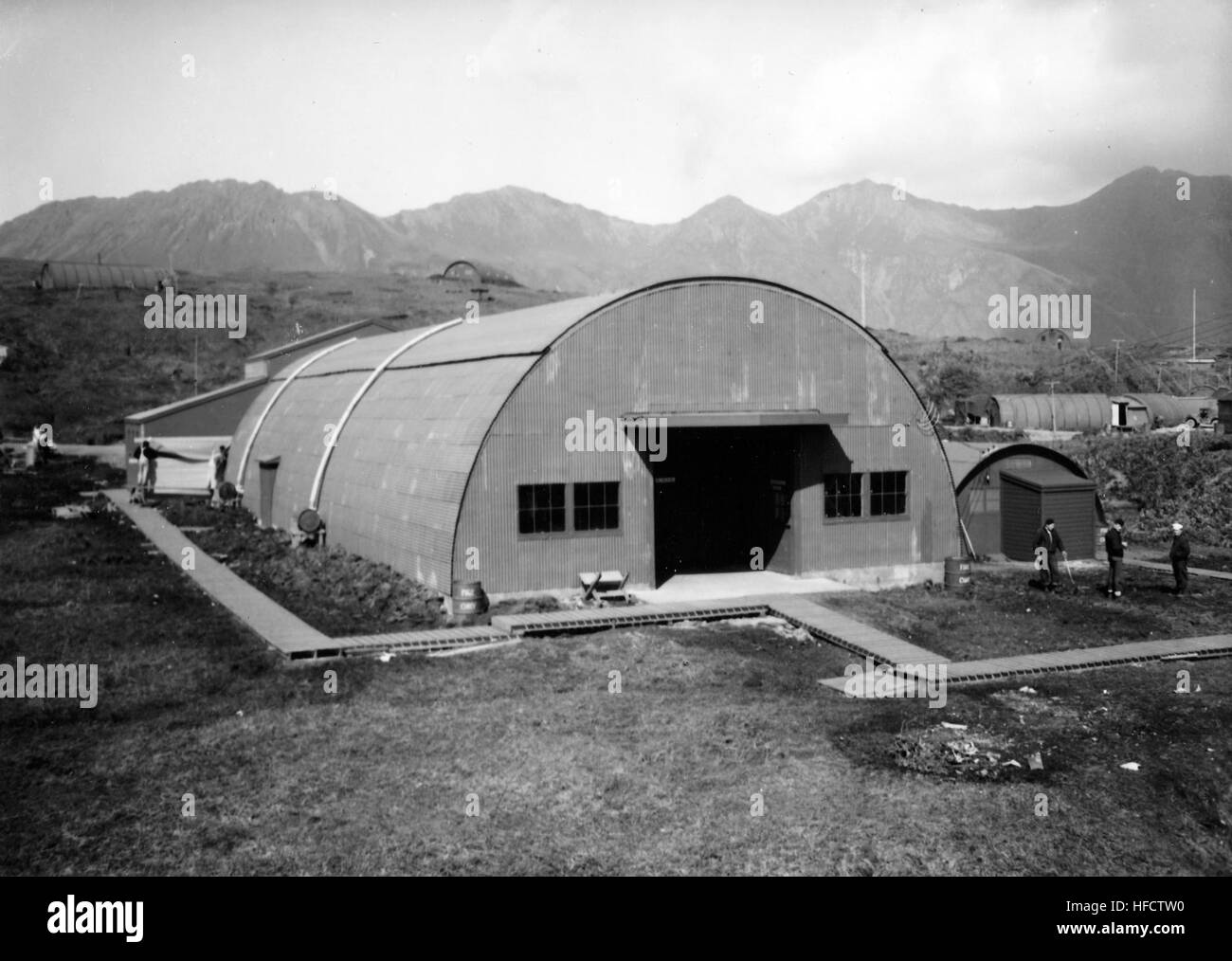 Eine Quonset-Hütte wurde um 1944 auf Attu Island fotografiert und repräsentiert temporäre militärische Strukturen, die während des Zweiten Weltkriegs für die Unterbringung von Personal und operative Unterstützung genutzt wurden Stockfoto