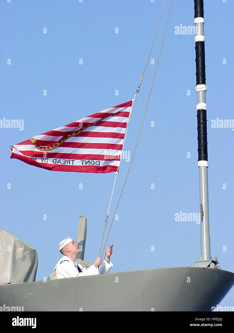 Am 11. September 2002 hebt der Operations Specialist 2nd Class den Navy Jack an Bord des Lenkraketenkreuzers USS Thomas S. Gates (CG 51) während der Morgenfarben. Die Navy Jack mit einer Klapperschlange über 13 rot-weißen Streifen wird während des Krieges gegen den Terrorismus auf Schiffen der US Navy anstelle der Union Jack geflogen. Stockfoto