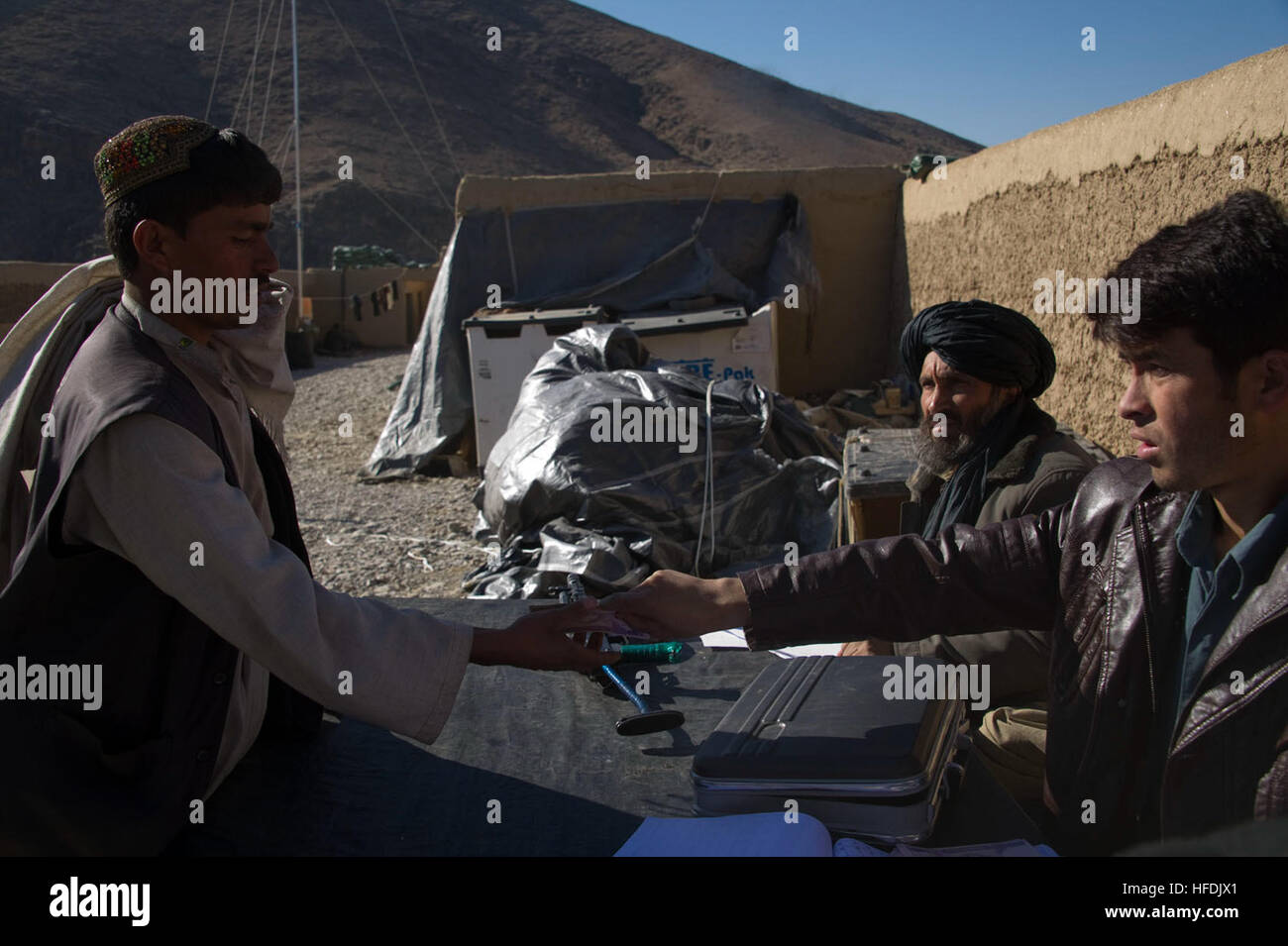 Pay-Agenten aus dem afghanischen Innenministerium übergeben ein Mitglied der afghanischen Polizei sein Monatsgehalt im Kajran Bezirk, Daykundi Provinz, Afghanistan, Jan. 20. Die ALP ist eine defensive, Community-orientierten Kraft, die ländlichen Afghanistan Sicherheit und Stabilität bringt. ALP sammeln Löhne 120120-N-JC271-105 Stockfoto