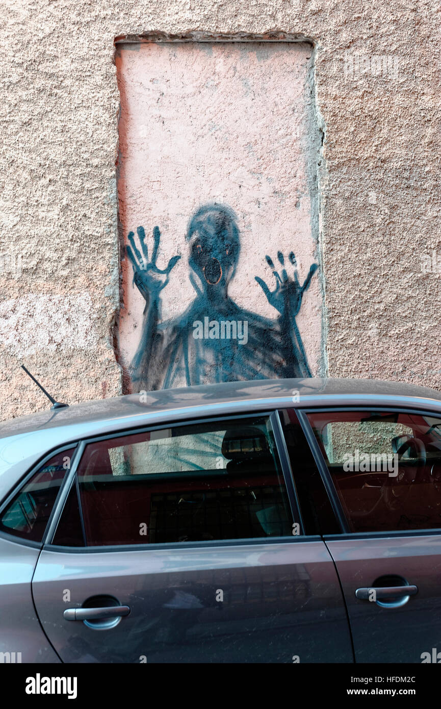 Clevere störenden Street Art einer Person schreien durch ein Fenster in eine Wand, über der Oberseite eines geparkten Autos auf einer Wand, Madrid Stockfoto