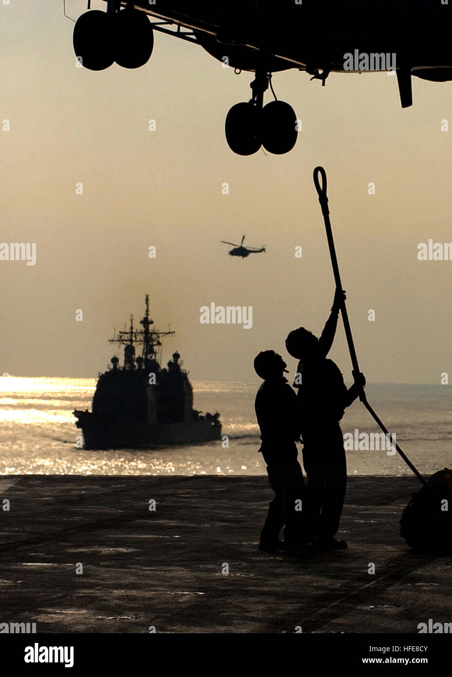 050115-N-2984R-019 Persischen Golf (14. Januar 2005) - Segler an Bord der USS Harry S. Truman (CVN-75) Haken ein Nachschub-Pendant zum Puma Helikopter während einer im Gange Nachschub mit dem Military Sealift Command (MSC) Bekämpfung Store Schiff USNS Saturn (T-AFS-9), während die Lenkflugkörper Kreuzer USS Monterey (CG-61) Manöver achtern des Trägers. Carrier Air Wing drei (CVW-3) ist ist an Bord der USS Harry S. Truman (CVN-75) begonnen und Luftnahunterstützung und Durchführung von Intelligenz, Überwachung und Aufklärungsmissionen über den Irak. Die Truman-Strike Group und CVW-3 sind auf eine regelmäßige Stockfoto