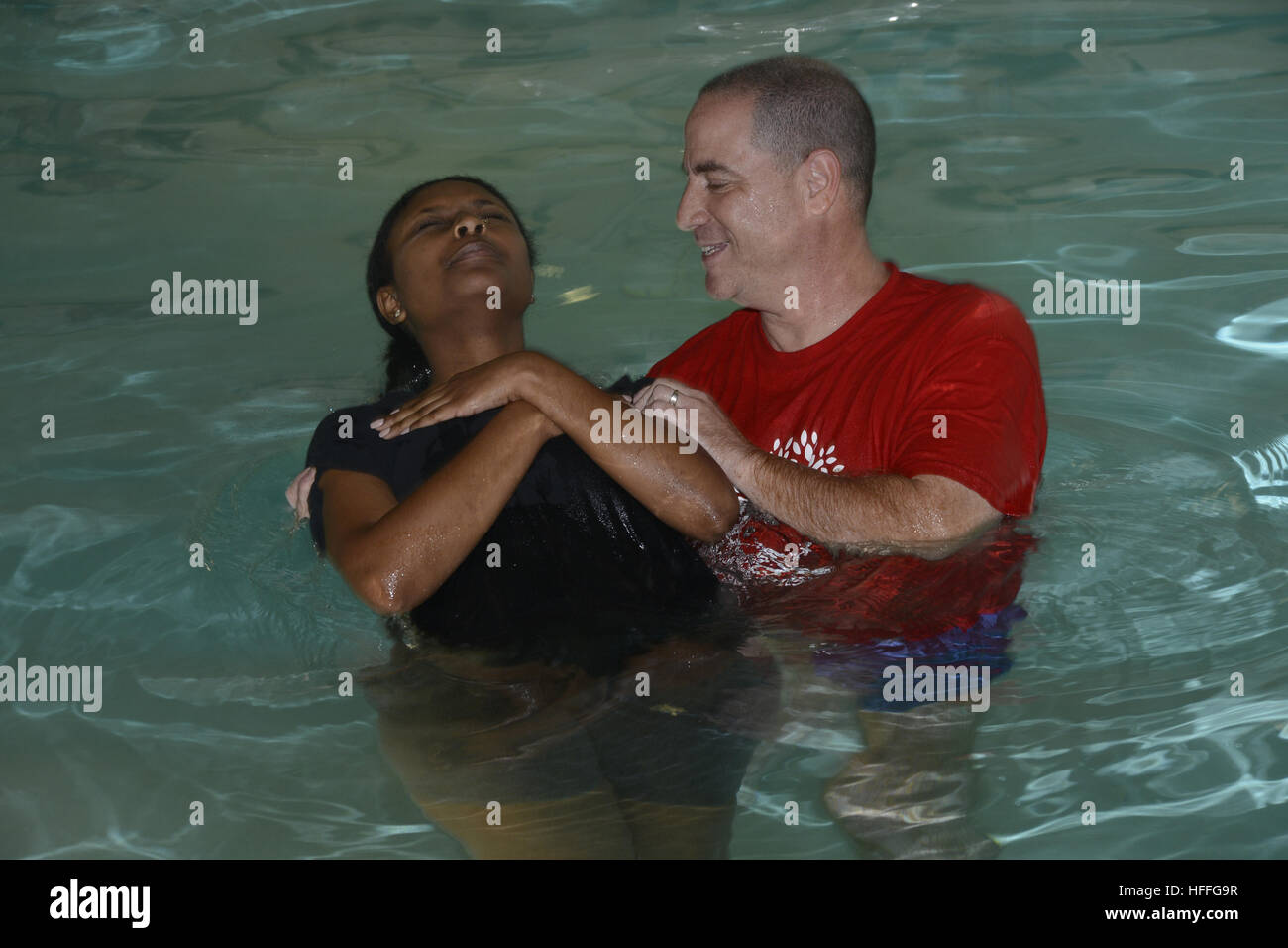 Ein Prediger tauft eine Frau während einer Taufzeremonie Stockfoto