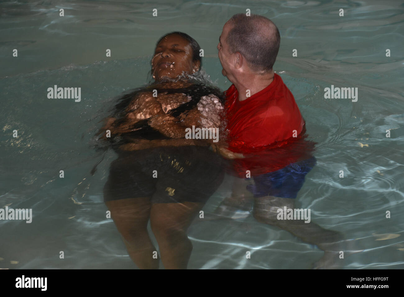 Ein Prediger tauft eine Frau während einer Taufzeremonie Stockfoto