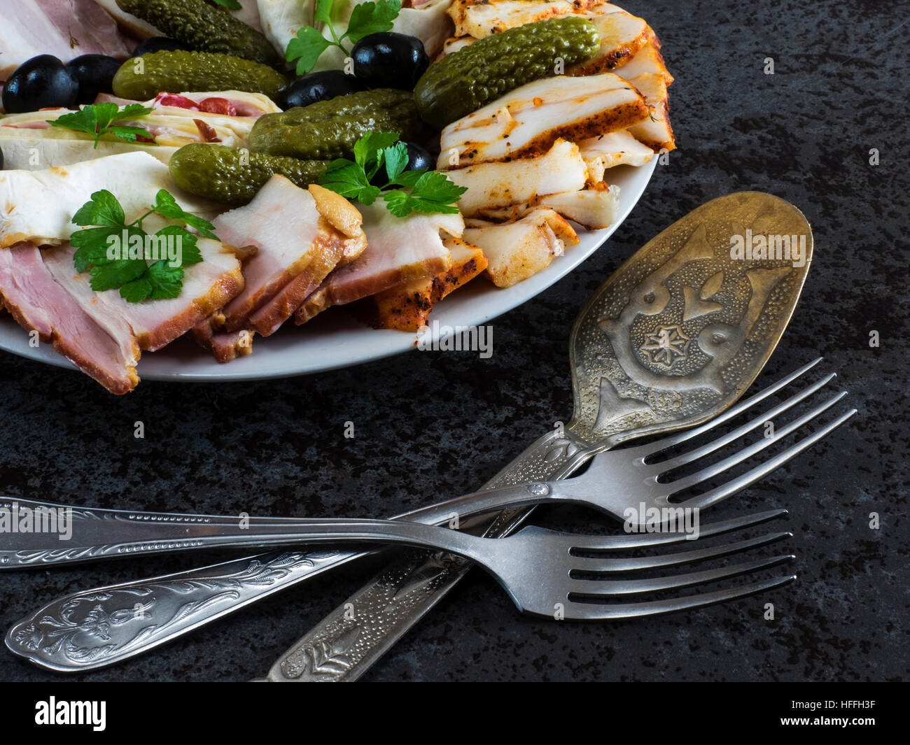 Teller mit Aufschnitt mit Schinken, Speck, Oliven und Gurken Stockfoto