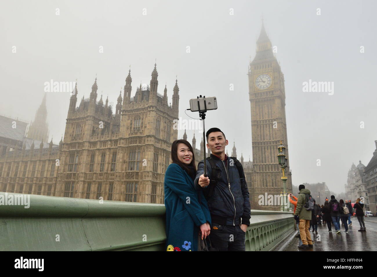 Ein paar ein Selbstporträt auf Westminster Bridge als Nebel hüllt Big Ben im Zentrum von London nach Meteorologen warnte der Sichtbarkeit als niedrig wie 100 m mit Nebel und Temperaturen unter Null, in Teilen von England. Stockfoto