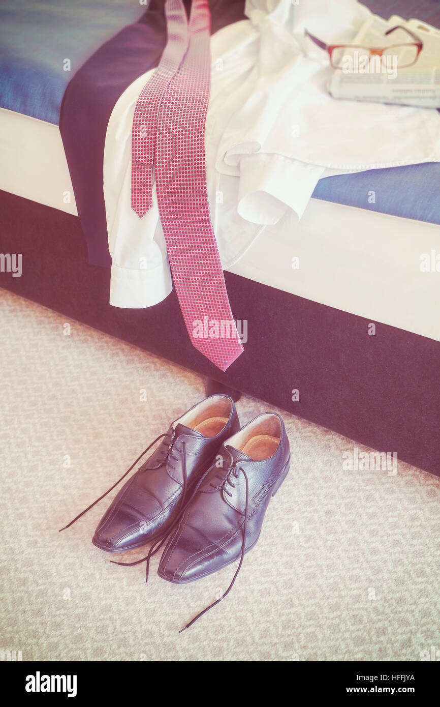 Vintage getönten männliche Schwarze Lederschuhe und Kleidung auf einem Bett. Stockfoto