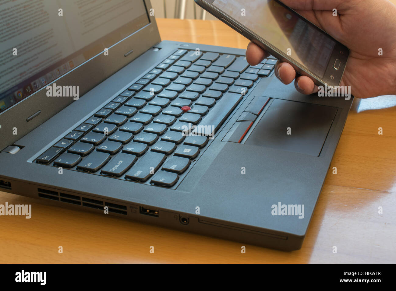 Seitenansicht auf Laptop mit Hand-Telefon auf dem Schreibtisch sitzen Stockfoto