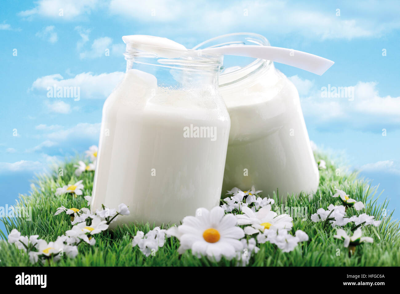 Glas Joghurt auf eine Blume Wiese, blauer Himmel Stockfoto