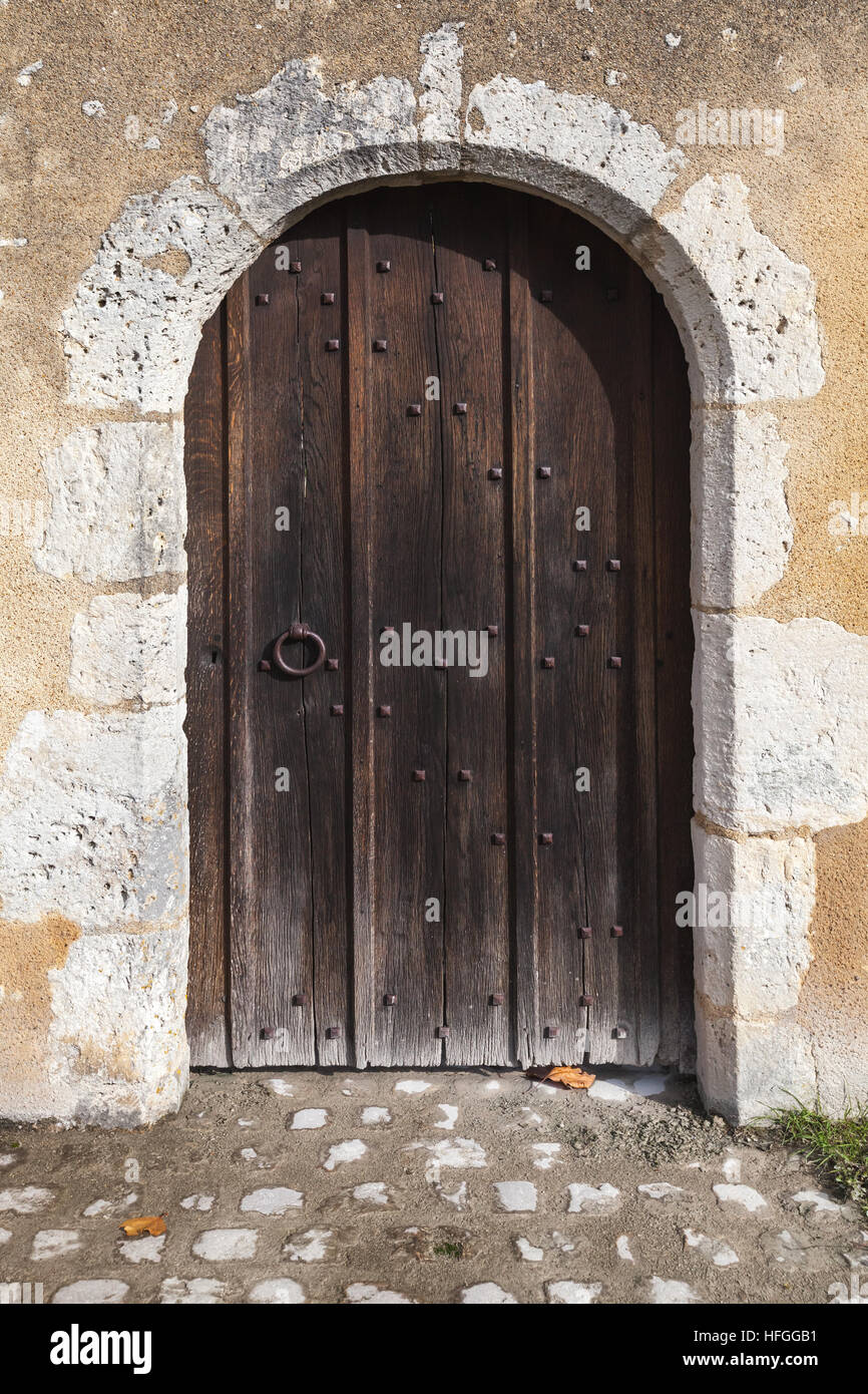 Dunkle Holztür mit Bogen in alten Steinmauer, Foto Hintergrundtextur Stockfoto