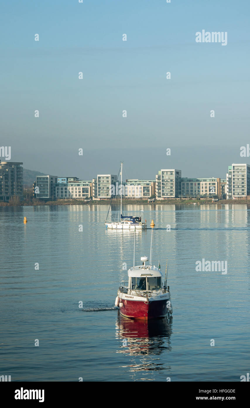 Den See in Cardiff Bay zeigt moderne Unterkunft Apartments, ein Boot und eine Yacht auf einem hellen, aber kalt winter Tag Südwales Stockfoto