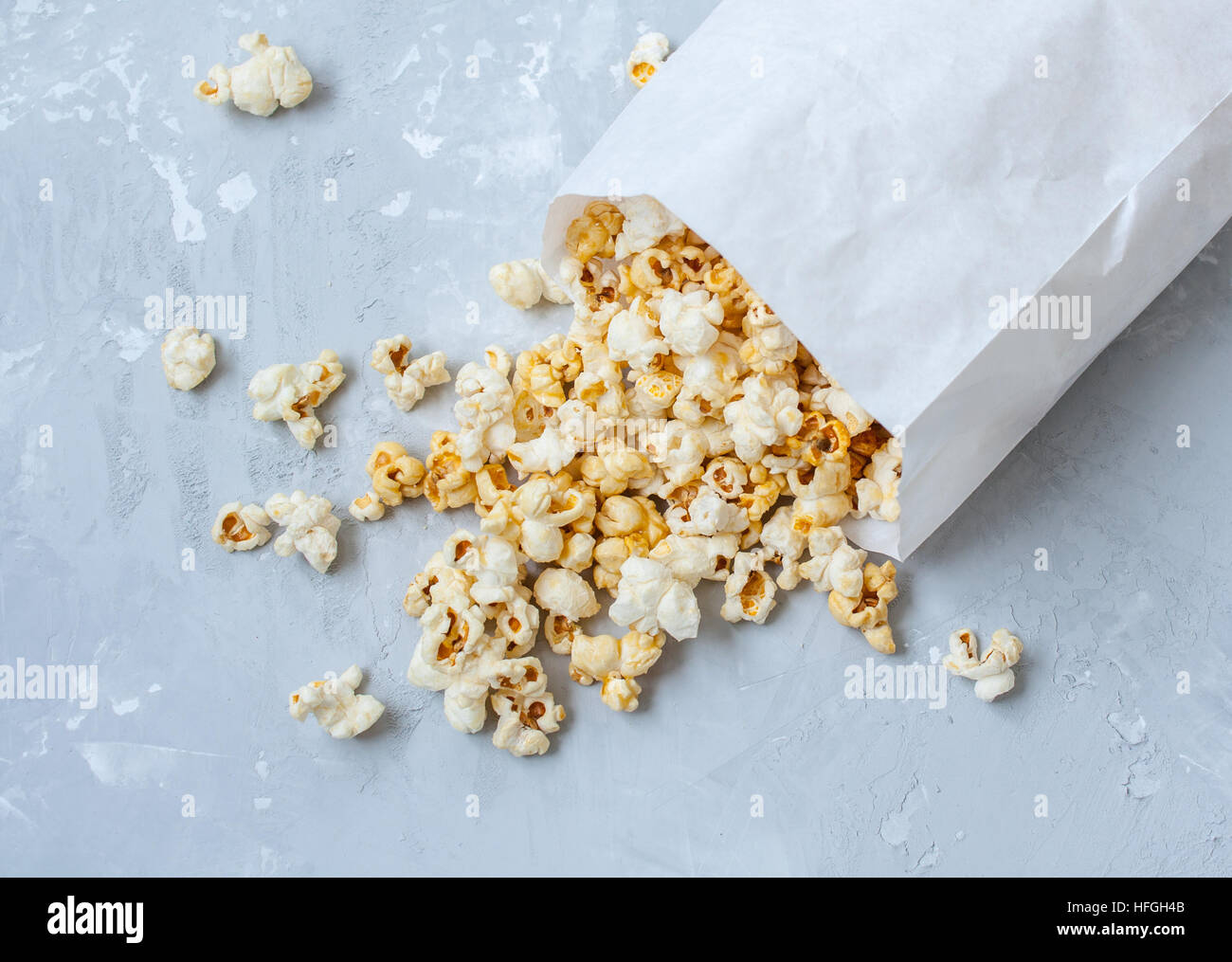 Süßen Karamell Popcorn in eine Papiertüte auf dem Beton grauen Hintergrund. Stockfoto