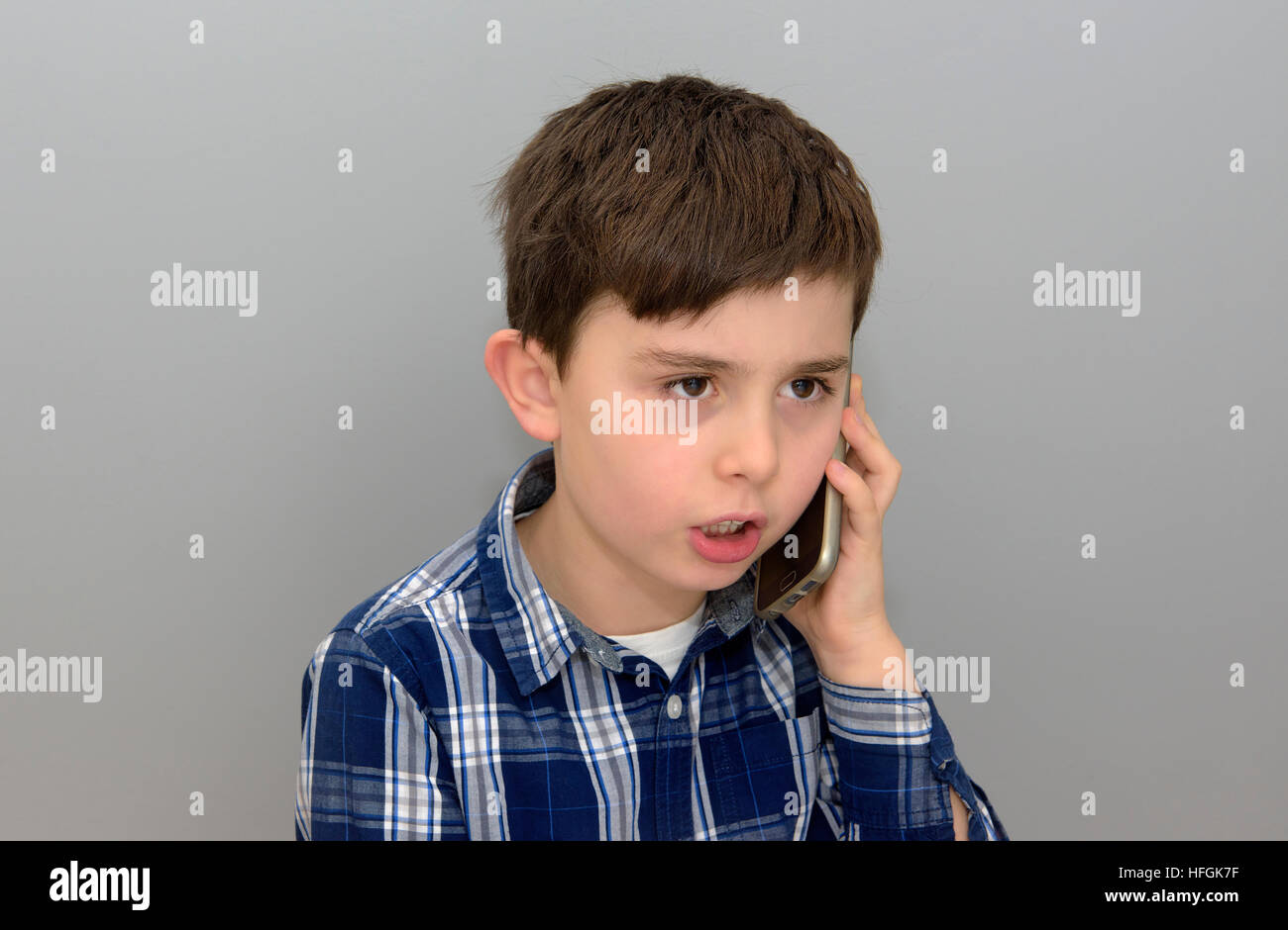 Porträt von Kind auf Smartphone sprechen hautnah. Schuss getroffen mit grauem Hintergrund Stockfoto