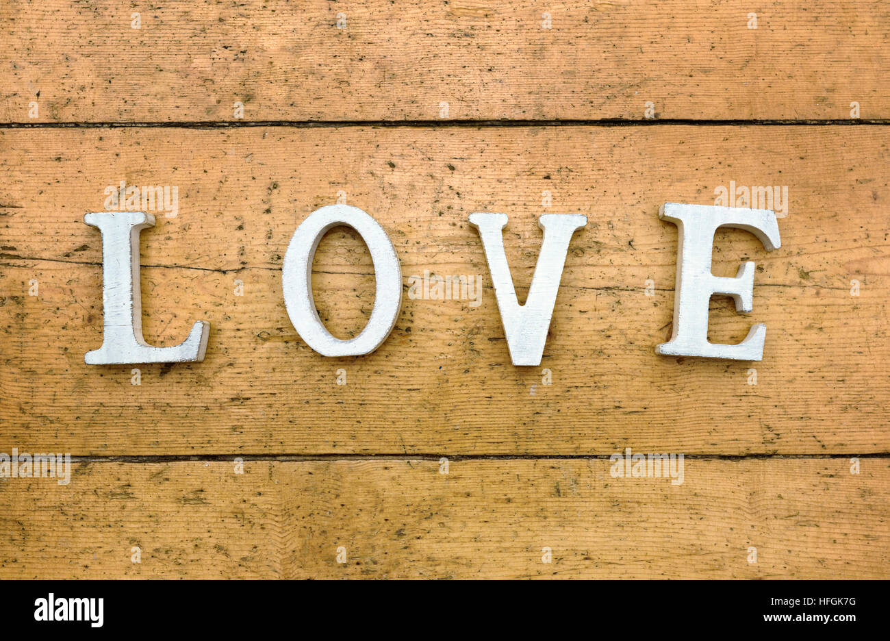 Buchstaben "Liebe" auf hölzernen strukturierten Hintergrund. Alte Holzdielen sind die Buchstaben Hintergrund weiß und in den Hauptstädten gefärbt sind Stockfoto