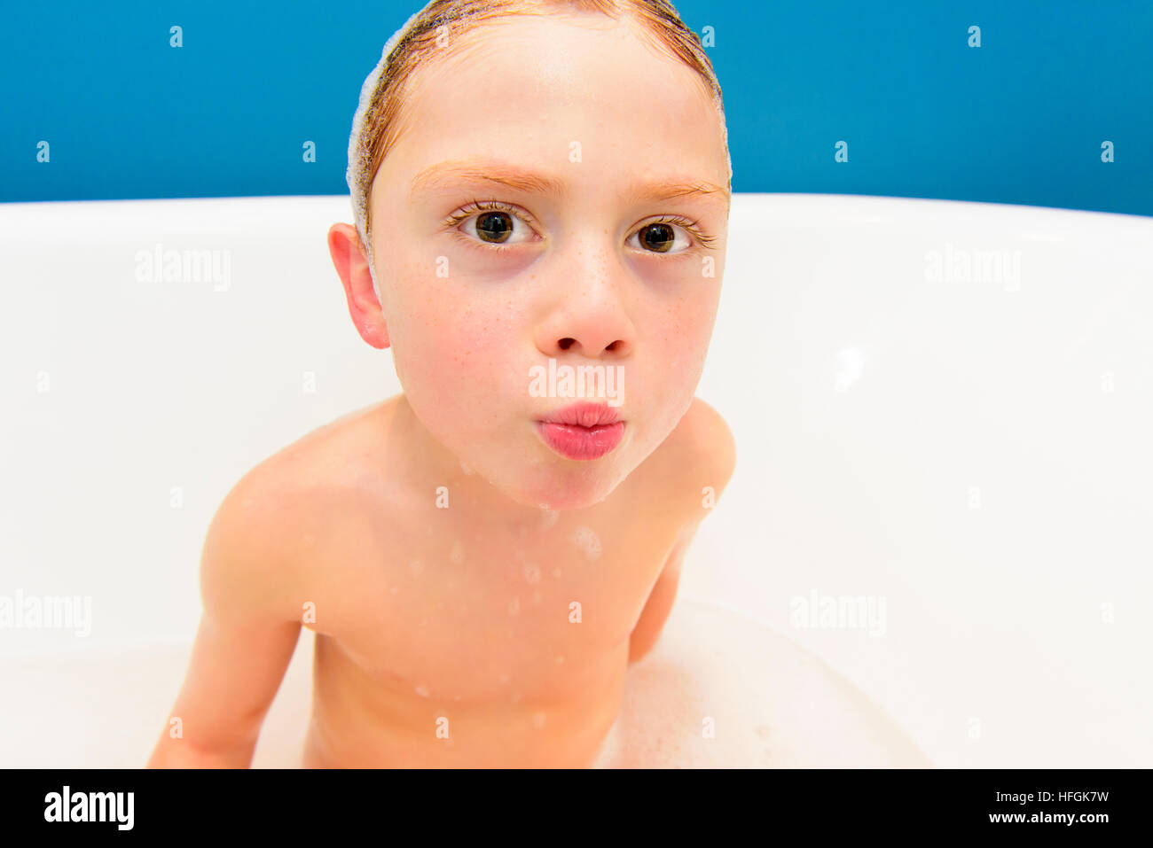 Junge Ingwer Junge herumwirbelte in der Badewanne und Gesichter an der Kamera Stockfoto