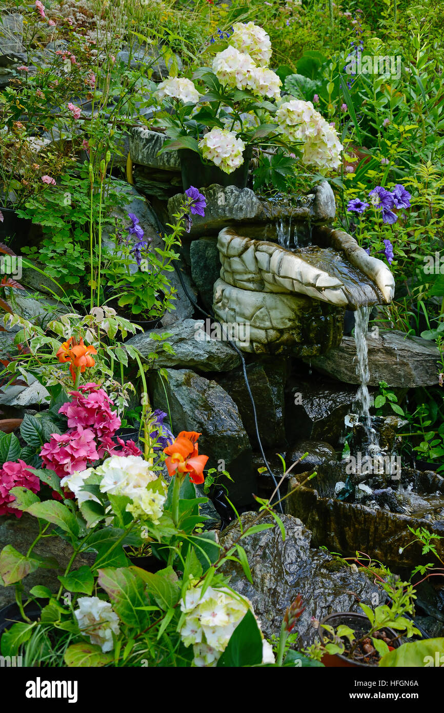 Kleine dekorative Brunnen im Garten mit Blumen geschmückt