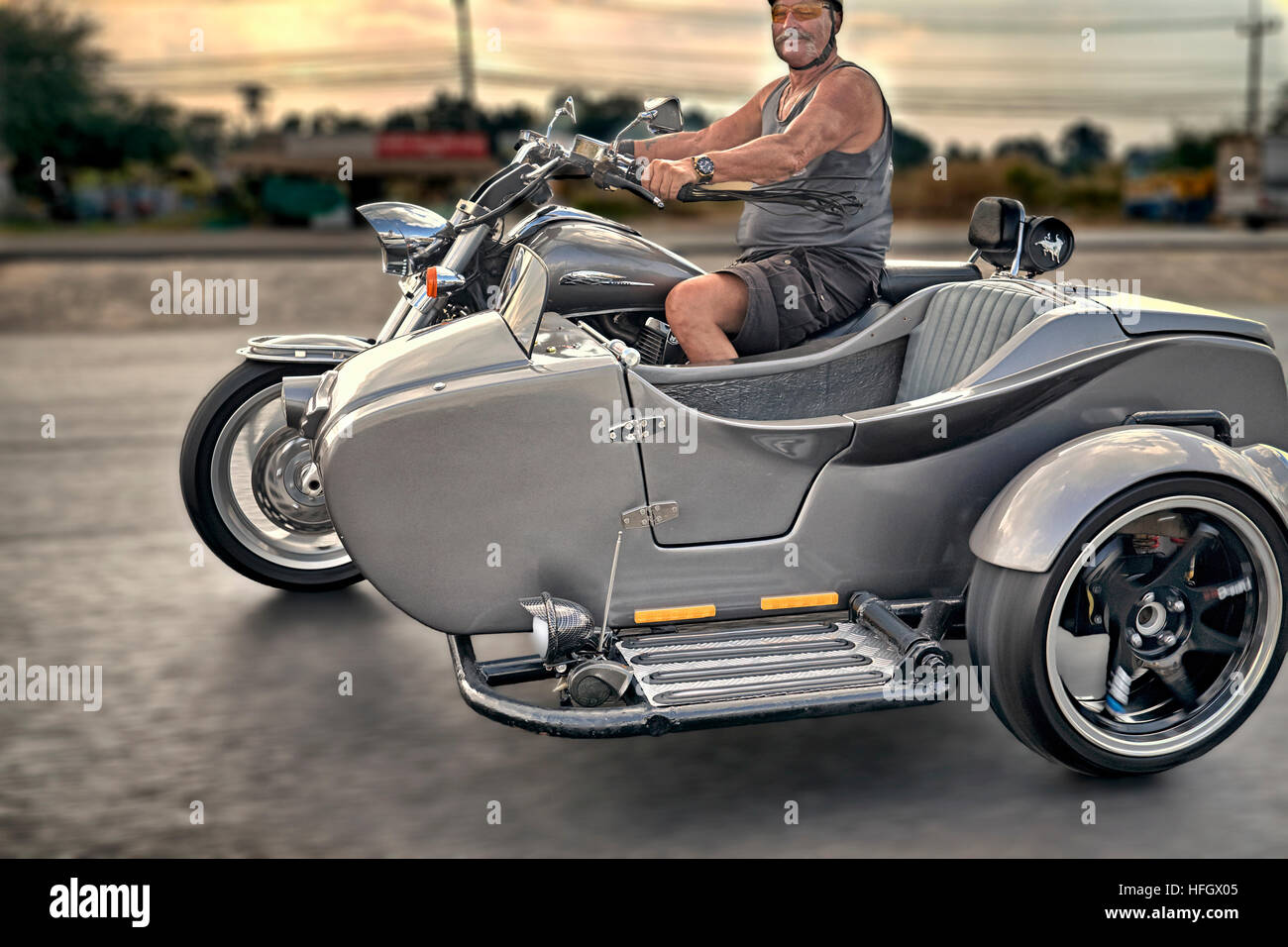 Motorrad-Beiwagen. Motorradfahrer, der maßgeschneiderte Motorrad- und Beiwagen entlang der Straße fährt Stockfoto