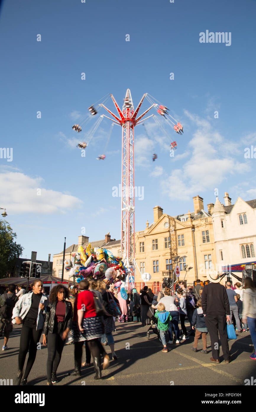 Menschen genießen die Skyrider St Giles Fair Oxford über Massen von Menschen zu Fuß Trog der Messe vor einem Oxford College unter blauem Himmel Stockfoto