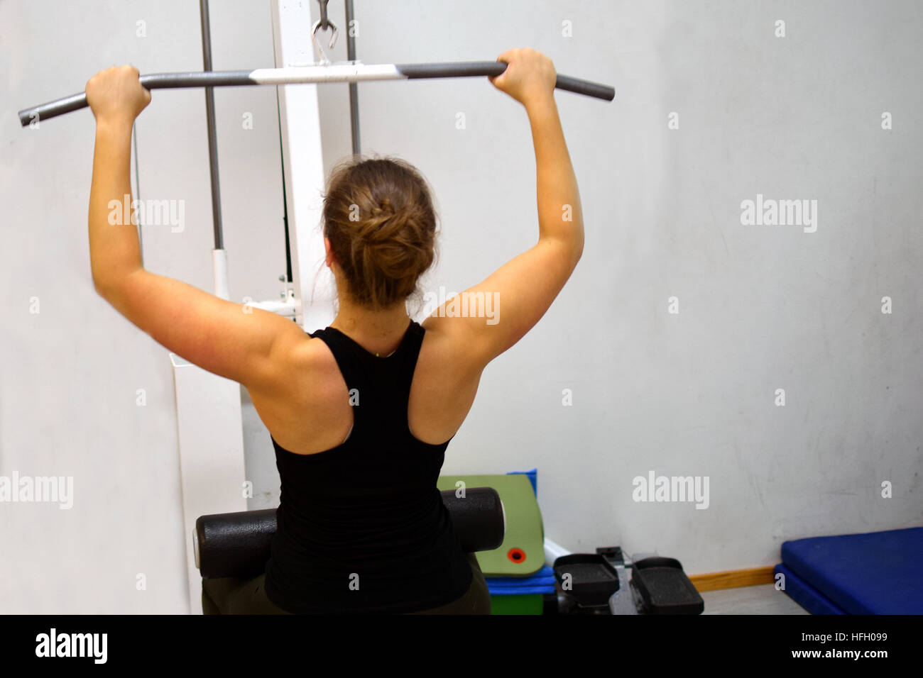 Frau in der Turnhalle. Trainieren ihre Muskeln des Rückens und der Arme mit Lat Pulldown-Trainingsgerät. Stockfoto