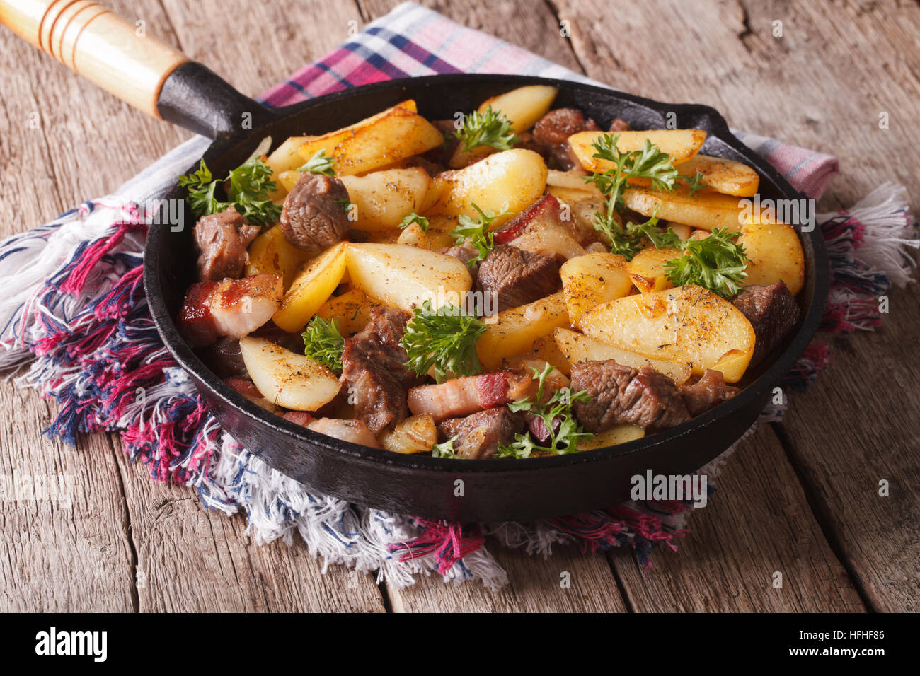 Heißes Land Bratkartoffeln mit Fleisch und Speck in einer Pfanne Großaufnahme serviert. Horizontale Stockfoto