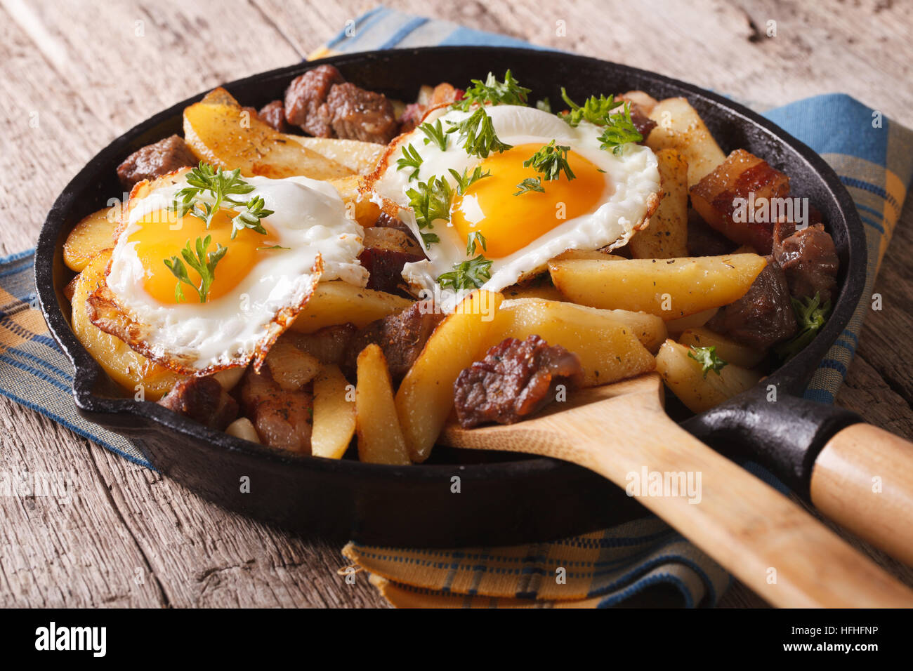 Europäische Küche: Bratkartoffeln mit Fleisch, Speck und Eiern in eine Pfanne Nahaufnahme. horizontale Stockfoto