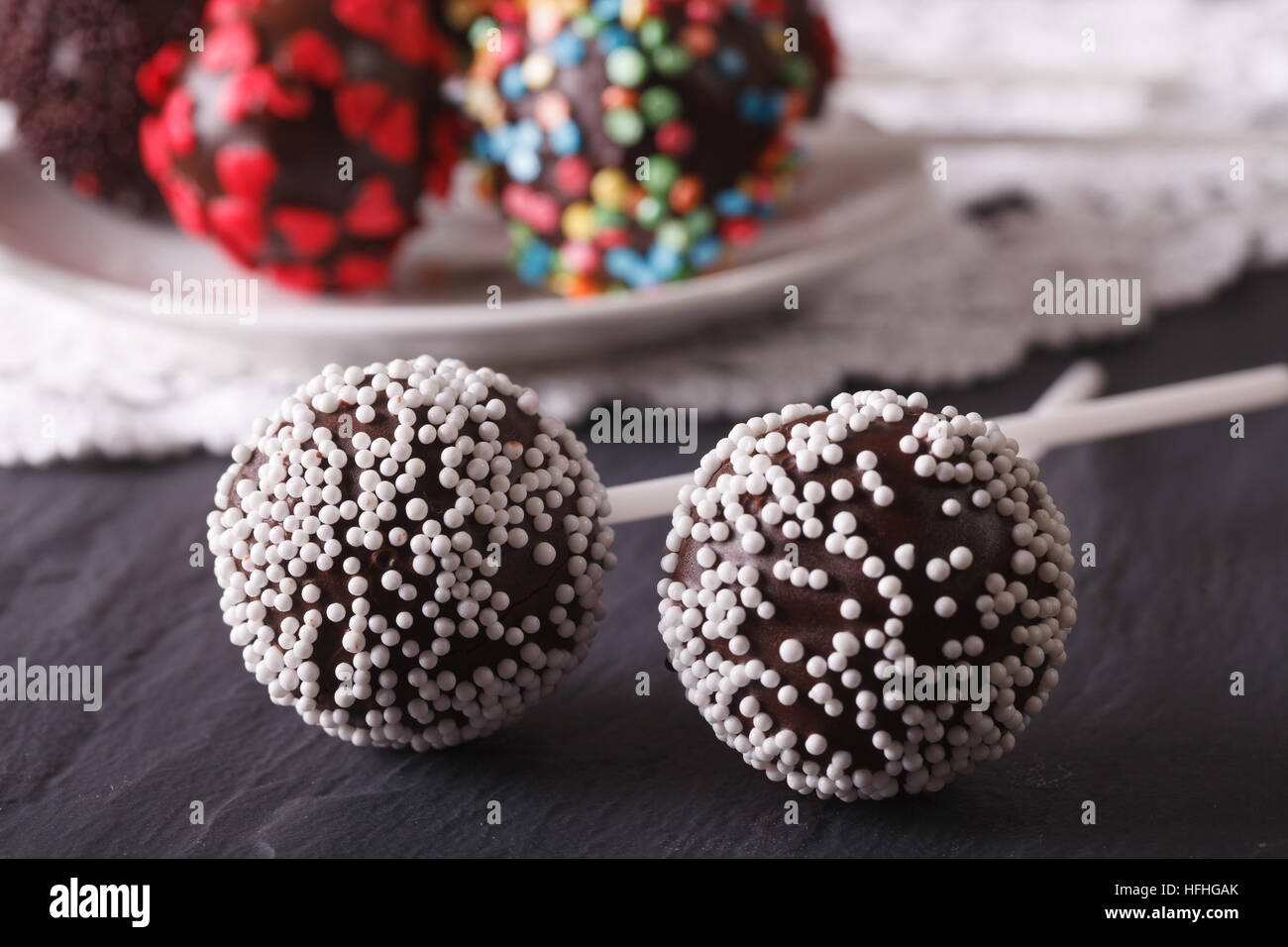 zwei Schoko-Cake Pops mit weißen Süßigkeiten Streusel Nahaufnahme auf dem Tisch. horizontale Stockfoto