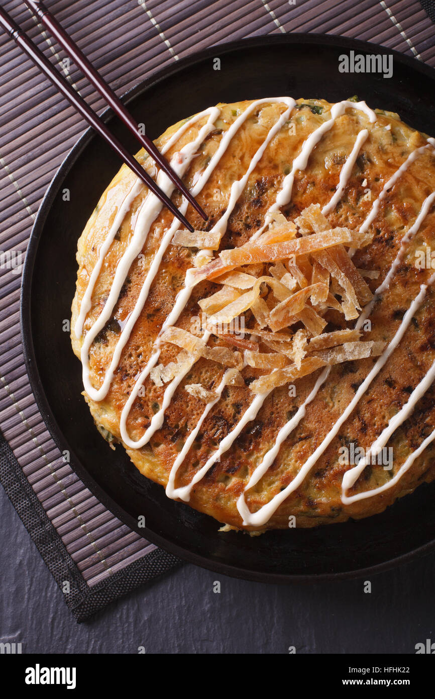 Traditionelles japanisches Essen: Okonomiyaki Nahaufnahme auf einer Platte. vertikale Ansicht von oben Stockfoto