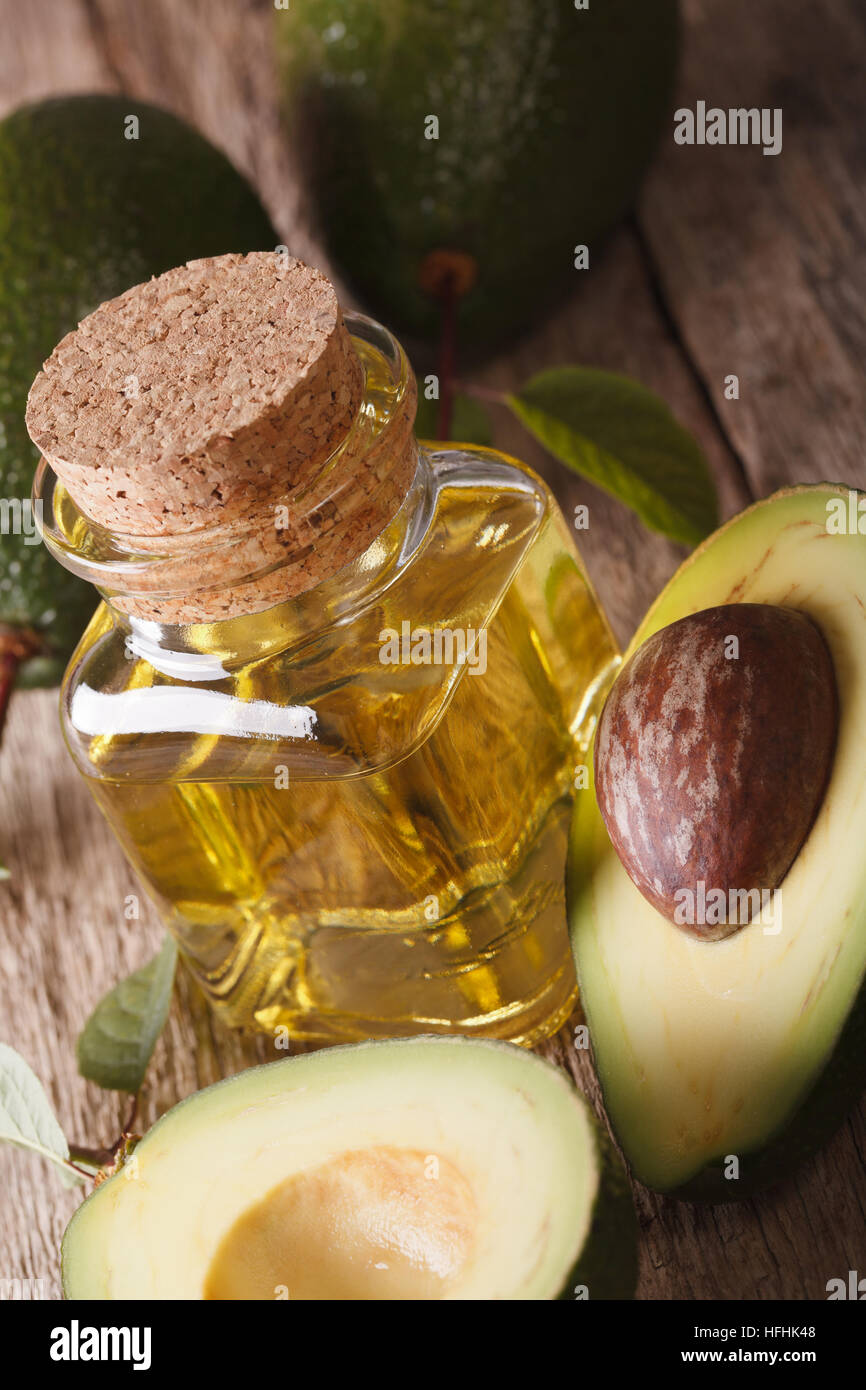 frische Avocado-Öl in eine Flasche aus Glas auf einem Holztisch Makro, vertikale Stockfoto