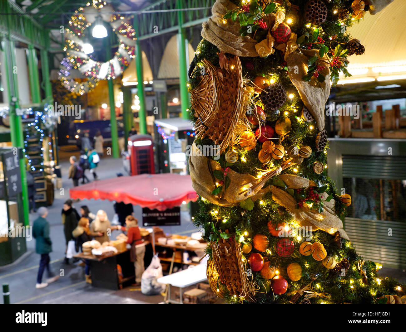 Erhöhte Sicht der späten Nacht Käse Marktstände und Verkostung Proben, Produkte unter dem Motto Weihnachten Kranz hängen im Vordergrund Borough Markt Southwark London SE1 Stockfoto