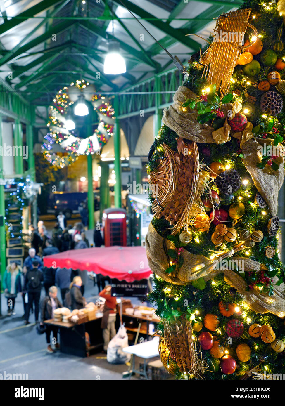 BOROUGH MARKET WEIHNACHTEN erhöhten Blick auf den späten Abend Käse Marktstände und Verkostung Proben, mit produzieren themenbezogene Weihnachten Kranz hängen in den Vordergrund Borough Market Southwark London SE1 Stockfoto