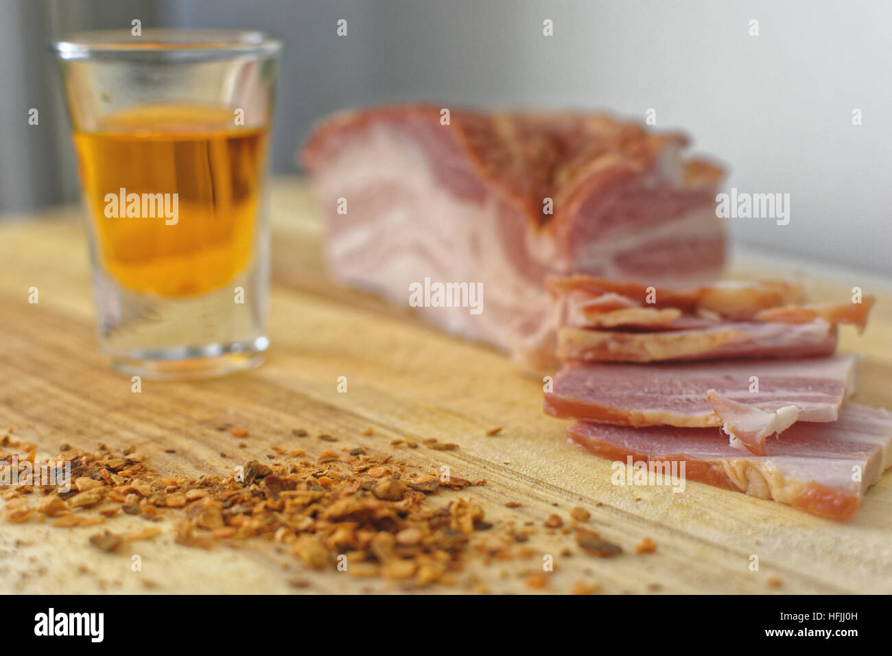 Frischer Speck auf einer Holzplatte mit einem Glas orange brandy Stockfoto