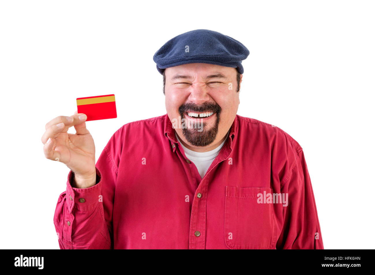 Fröhlichen Mann mittleren Alters mit einem Spitzbart trägt ein rotes Hemd und Kappe hält eine Bankkarte mit einem strahlenden Lächeln und lachen, als er die Elemente h stellt sich vor Stockfoto