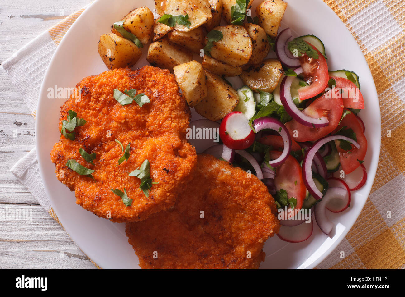 Wiener Schnitzel, Bratkartoffeln und Salat auf den Tisch-Nahaufnahme. horizontale Ansicht von oben Stockfoto