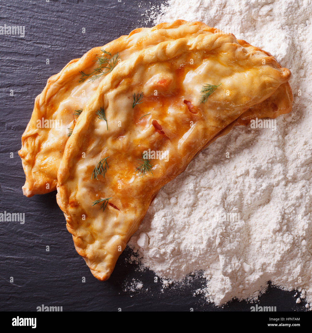 Italienische Küche: Pizza Calzone und Weißmehl Nahaufnahme auf dem Tisch. Ansicht von oben Stockfoto