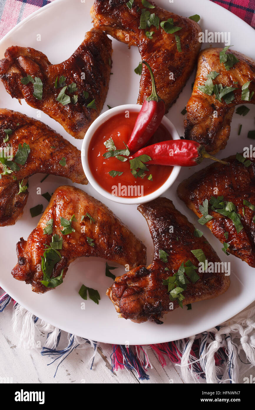 Gegrillte Hühnerflügel mit Chili-Sauce auf einer Platte Makro heiß. vertikale Ansicht von oben Stockfoto