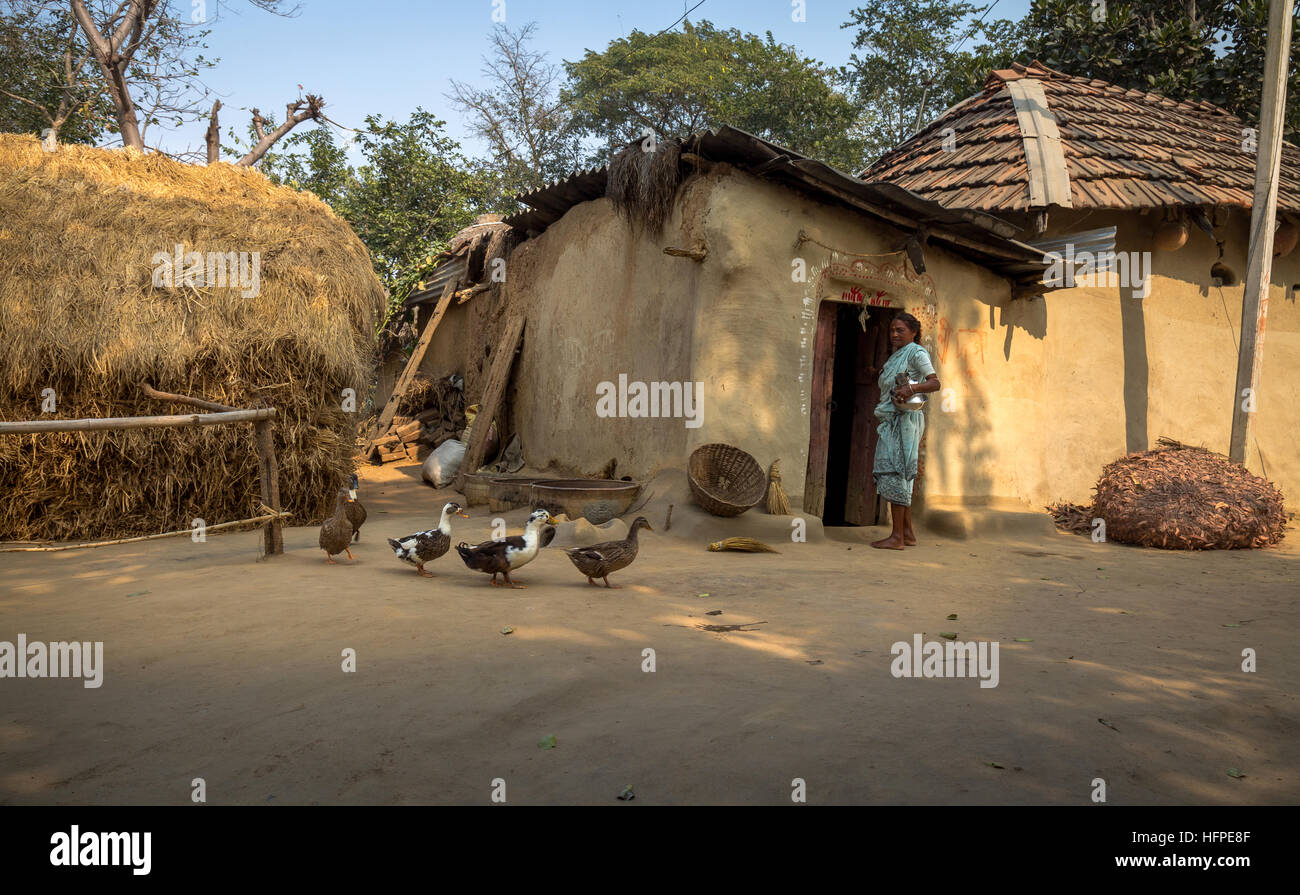 Indische Bauerndorf in Bankura, West-Bengalen mit Lehmhütten, Geflügel und eine alte Indianerin auf dem Hof stehen. Stockfoto
