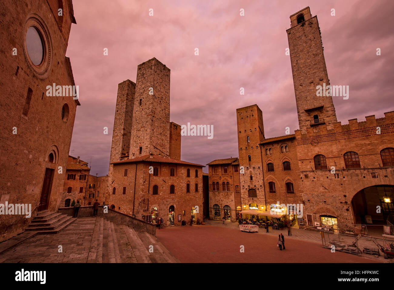Untergehende Sonne schaffen ein rotes Glühen über Piazza del Duomo und Türme von San Gimignano in der Dämmerung, Toskana, Italien Stockfoto