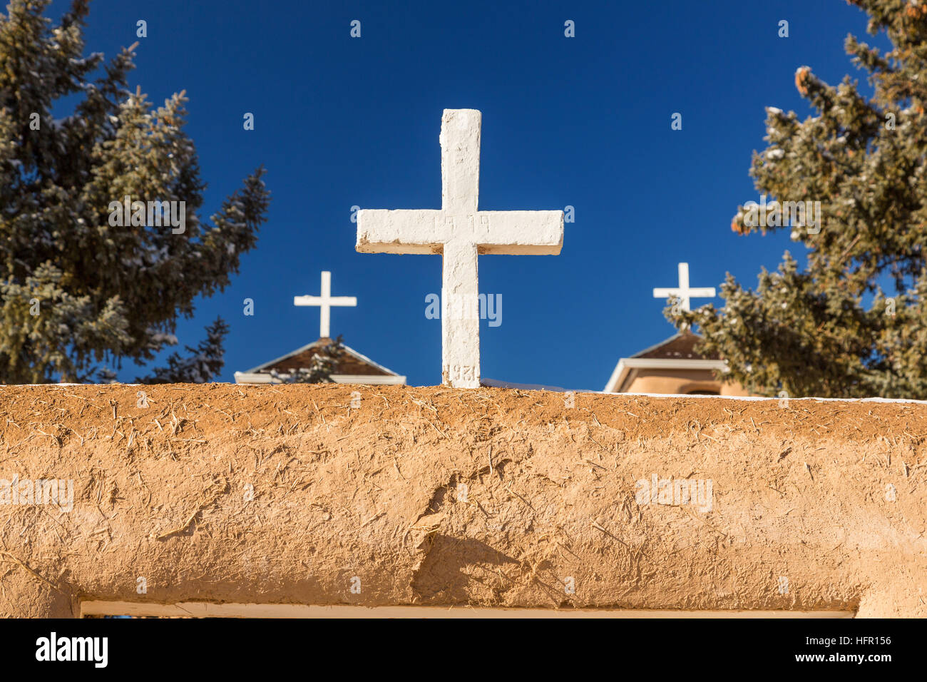 Ein weißes Kreuz auf die historischen San Francisco de Asis Missionskirche in Ranchos de Taos Plaza, Taos, New Mexiko. Die Adobe-Kirche erbaut im Jahre 1772 und berühmt geworden in Gemälde des Künstlers Georgia O'Keeffe. Stockfoto