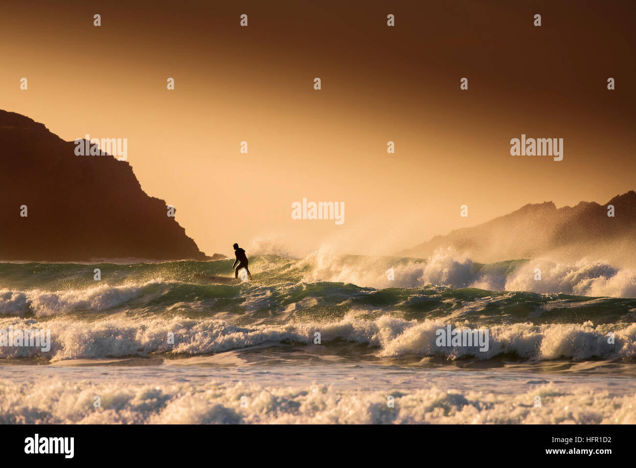 Surfen während eines goldenen Sonnenuntergang am Fistral in Newquay, Cornwall. Stockfoto