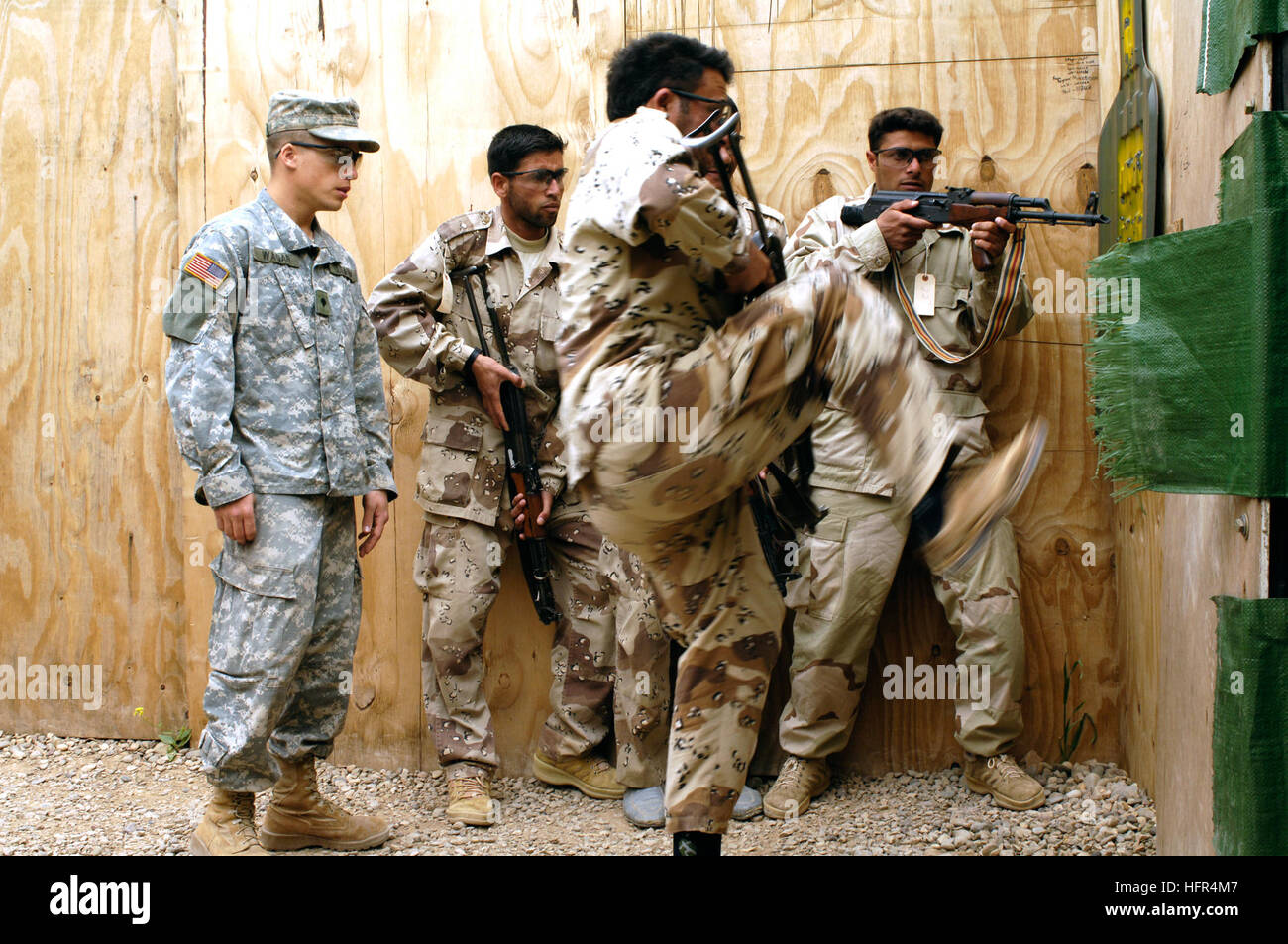 060412-N-4614W-018 vorwärts operative Basis McHenry, Irak (12. April 2006) - ein Irak-Armee Soldat aus 5. Bataillon, Tritte in einer Tür, im Inneren des Hauses zu töten, als Armee Spc. Nate Wagar, Stabskompanie, 1. Bataillon, 327th Infanterie-Regiment zugewiesen beobachtet, während die militärischen Operationen im urbanen Gelände (MOUT), Kurs. Die einwöchige (MOUT) Kurs ist repetitiv und rasanten geben die irakischen Soldaten Muskelgedächtnis, erfolgreich eine Residenz, schnell und sicher einzugeben. Der Kurs beinhaltet Einschießen von Waffen, live Kill-Haus Brandszenarien und montierte Waffensysteme. U.S. Navy Photo by J Stockfoto