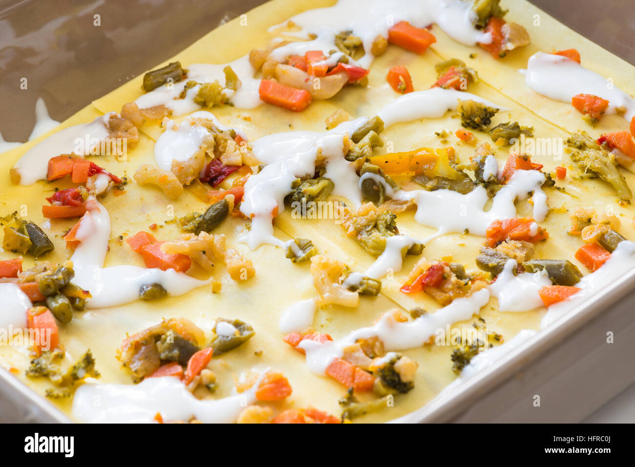 Vorbereitung vegetarische Lasagne mit Karotten, Zwiebeln, Erbsen, Brokkoli, Paprika, Blumenkohl Stockfoto