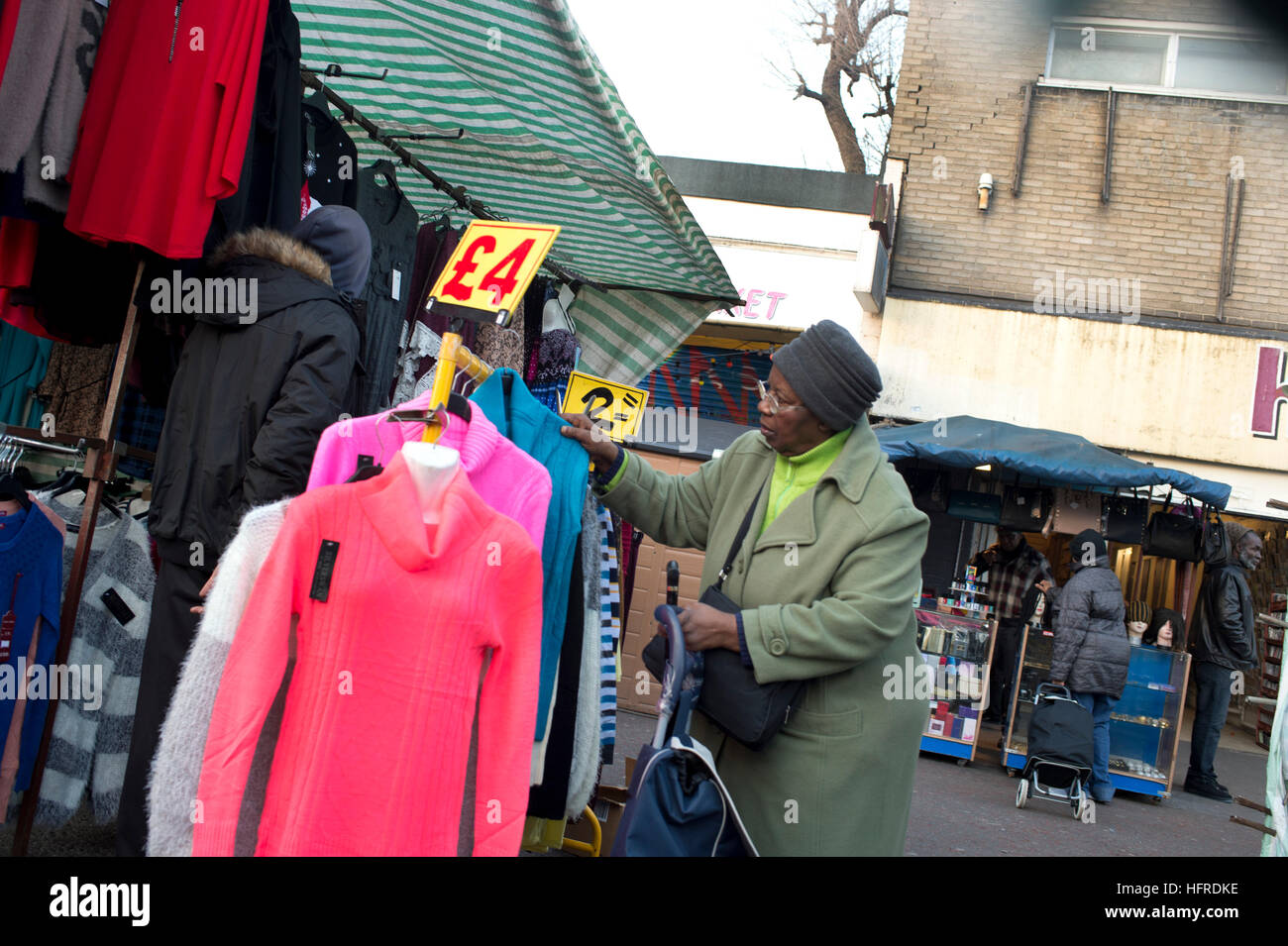 Hackney. Ridley Straße Markt. Ein Afro-Karibische Frau Shopper untersucht die Schnäppchen-Kleiderständer Stockfoto