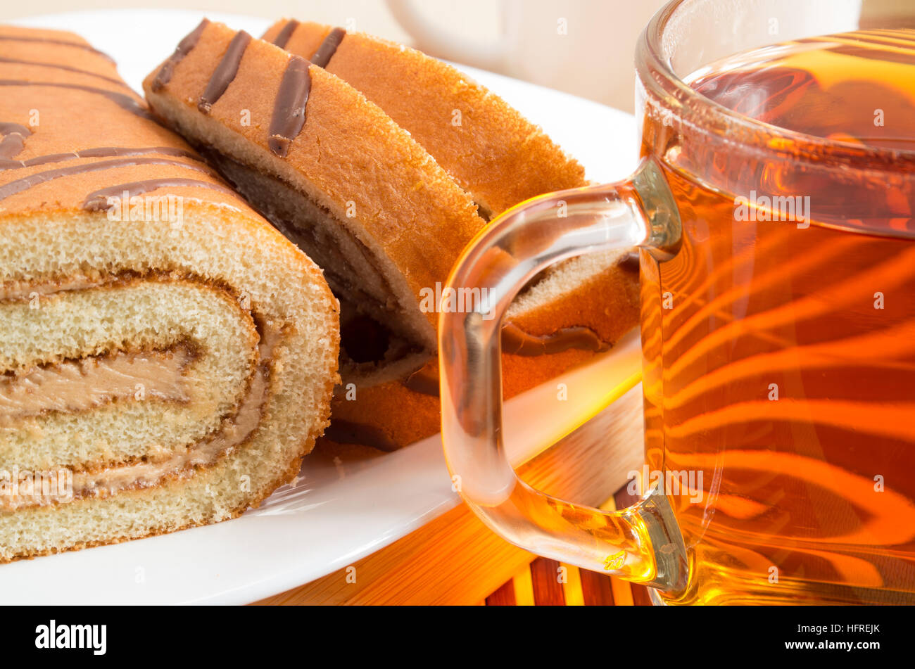 Biskuit mit Schokofüllung und transparente Tasse heißen Tee hautnah. Stockfoto