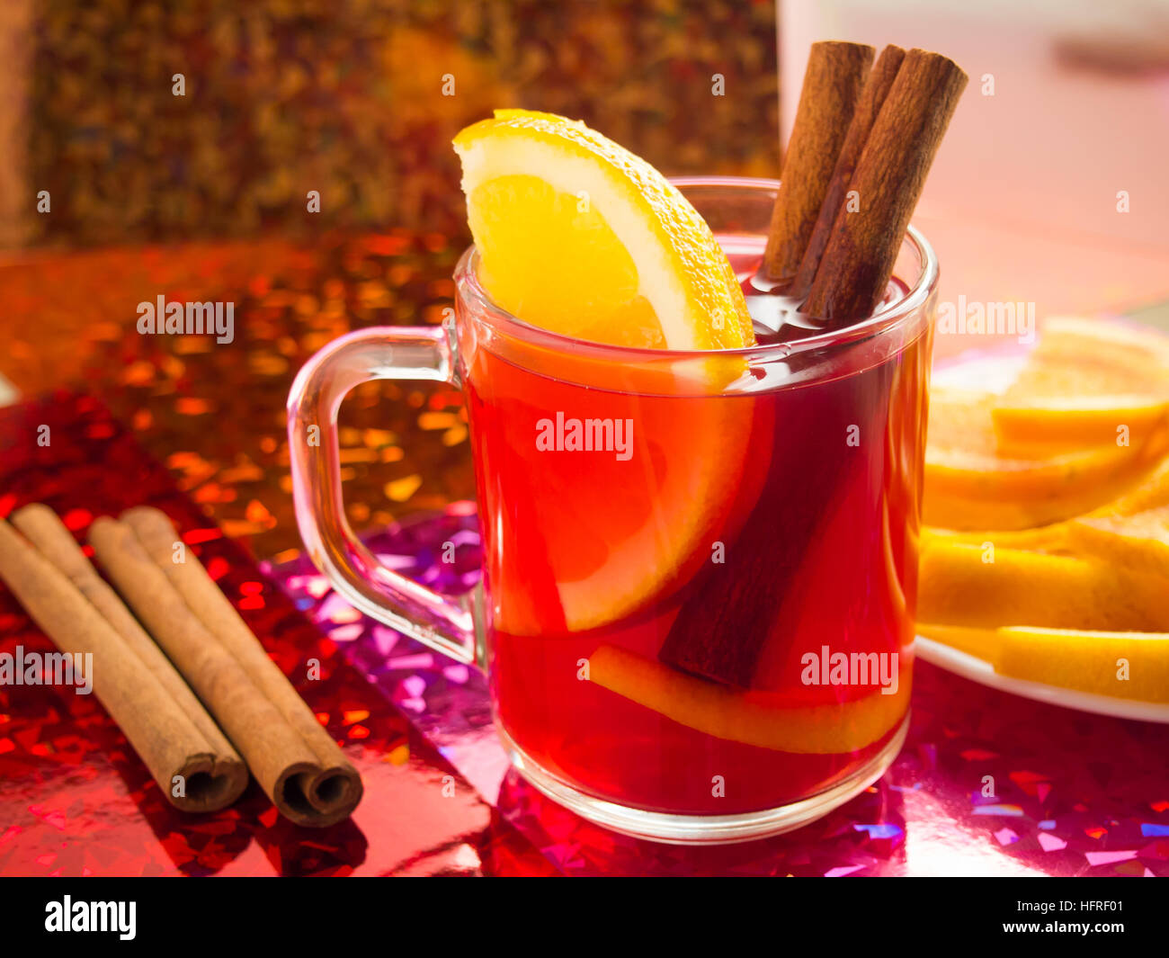 Transparente Tasse Tee mit Zitrusfrüchten, Zimt und Orange, hell glänzenden Hintergrund Stockfoto