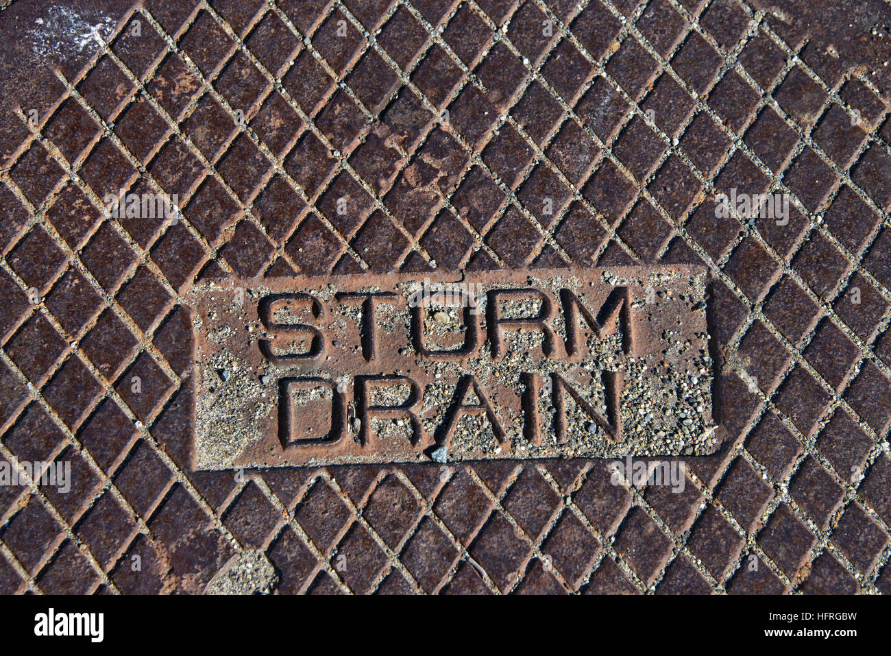 Rustikale Grunge Storm Drain Kanaldeckel hautnah auf Storm Drain geschnitzten Buchstaben Stockfoto